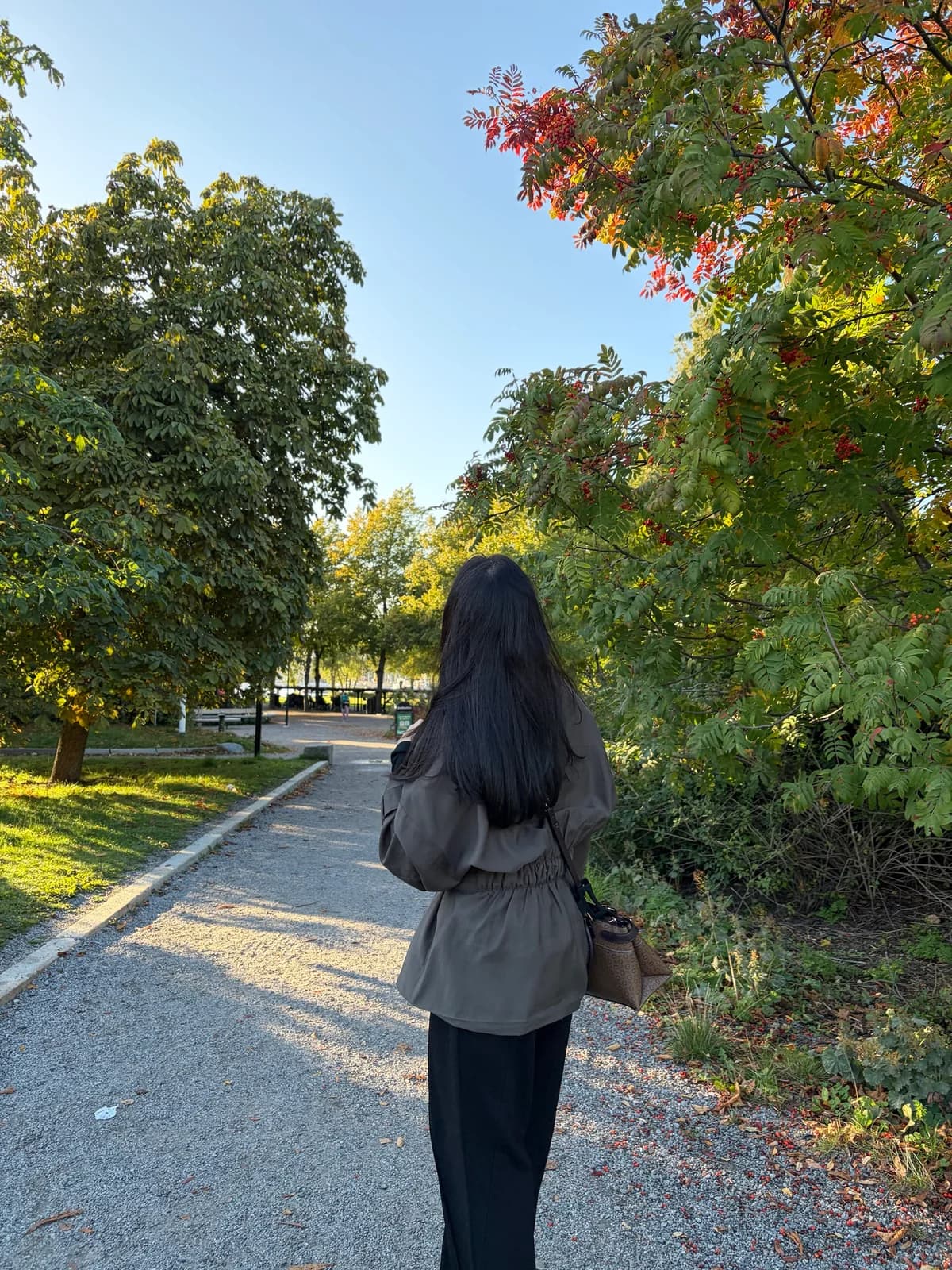 Faiza walking on a tree-lined path in autumn in Stockholm